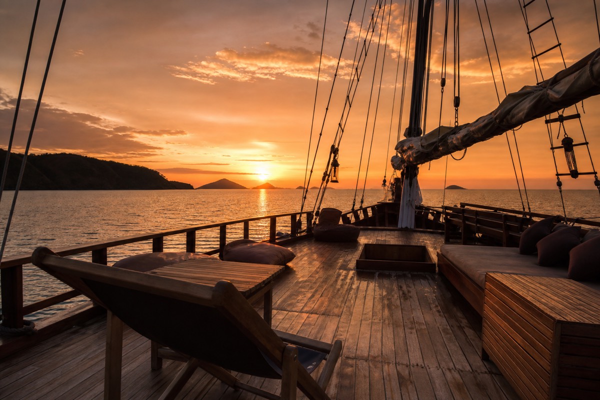 A Phinisi liveaboard deck at sunset, the boat style used across Komodo and Raja Ampat